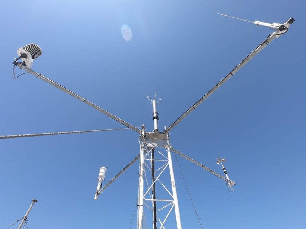 Vejrstation med anemometre og meteorologiske instrumenter mod blå himmel