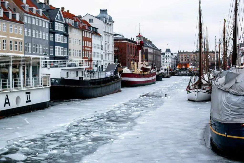 Sne i København — frosne kanaler med både i vinterklædt by