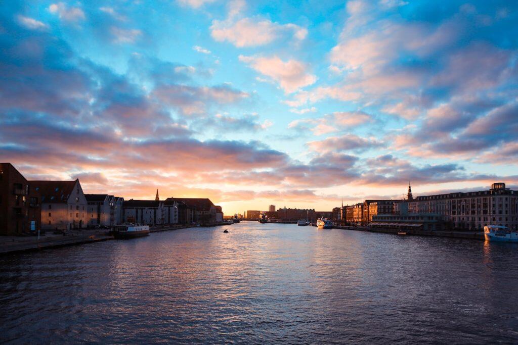 Solnedgang over Københavns havn med dramatisk skydække og refleksioner i vandet